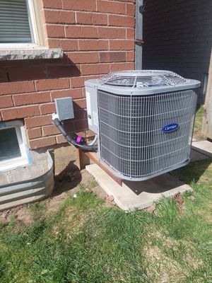 Carrier central air conditioner installed beside a brick home