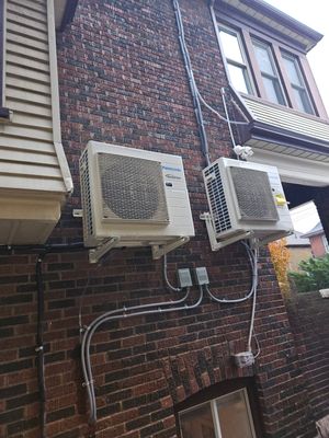 Two Panasonic ductless mini-split outdoor units installed on a brick exterior wall