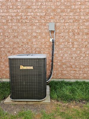 Ducane central air conditioner installed beside a brick home